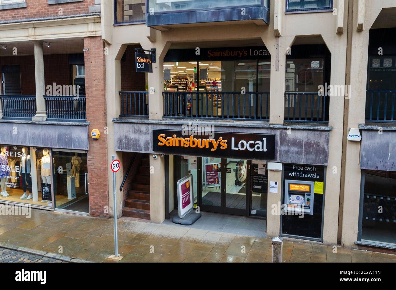 Chester, UK: Jun 14, 2020: A poster with social distancing instructions is displayed outside a Chester city centre branch of Sainsbury's Local. Stock Photo