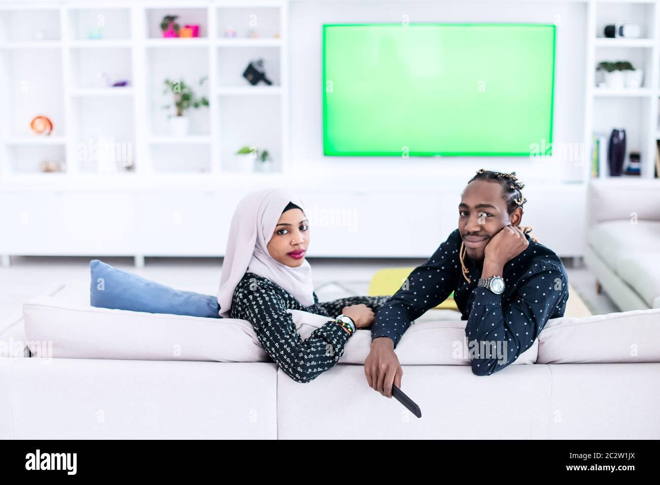 African Couple Sitting On Sofa Watching TV Together Stock Photo - Alamy