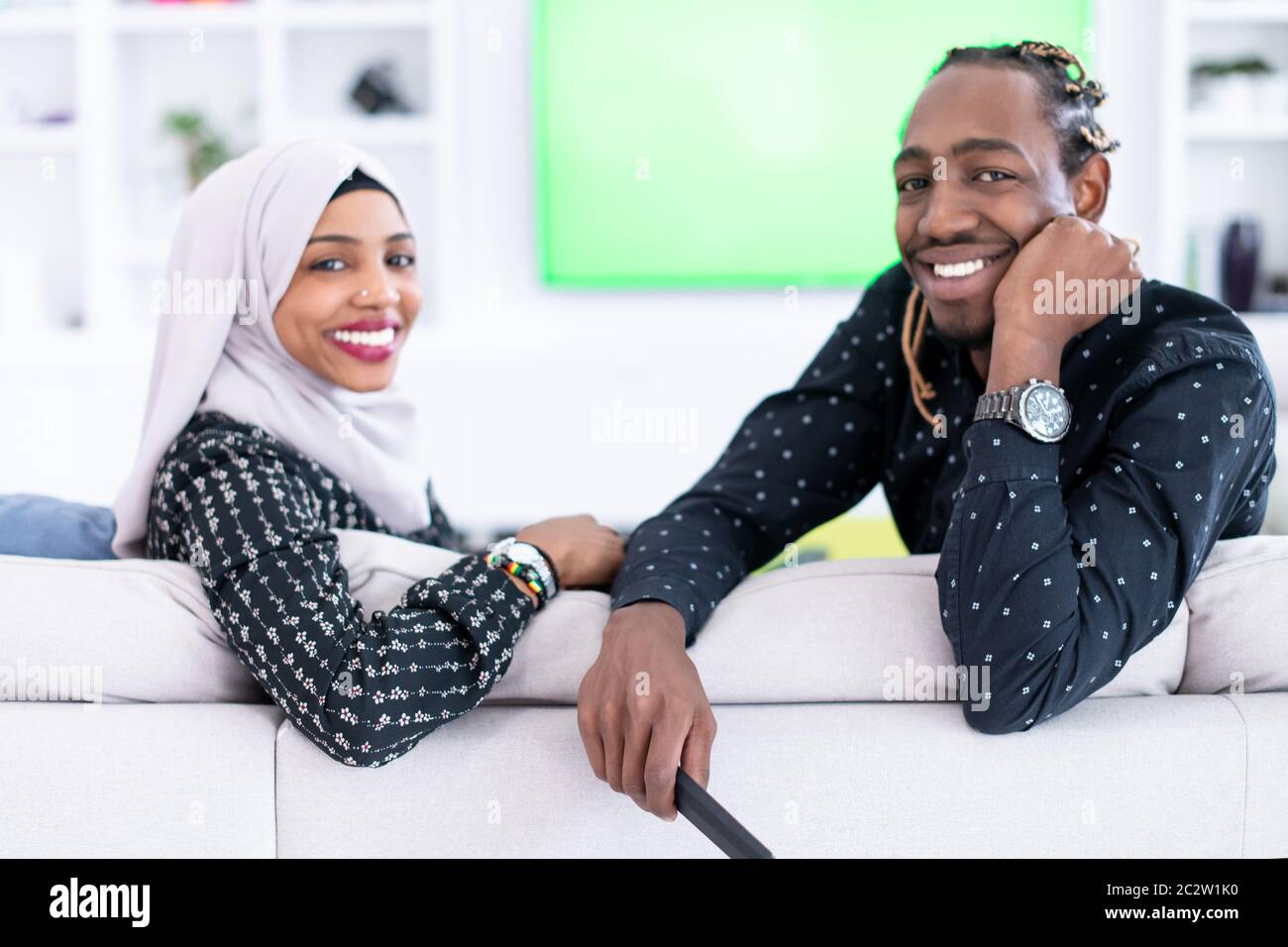 African Couple Sitting On Sofa Watching TV Together Stock Photo - Alamy