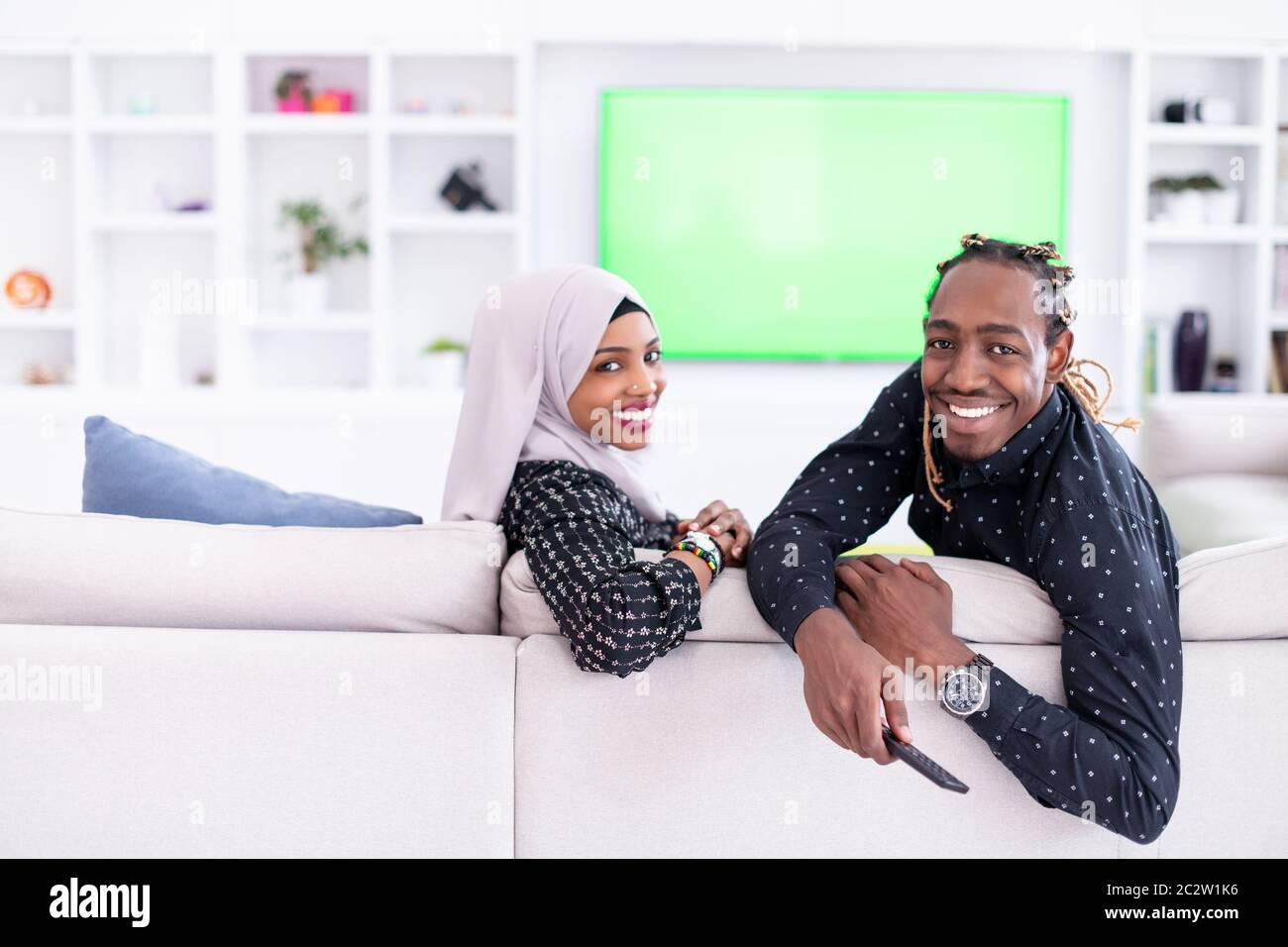 African Couple Sitting On Sofa Watching TV Together Stock Photo - Alamy