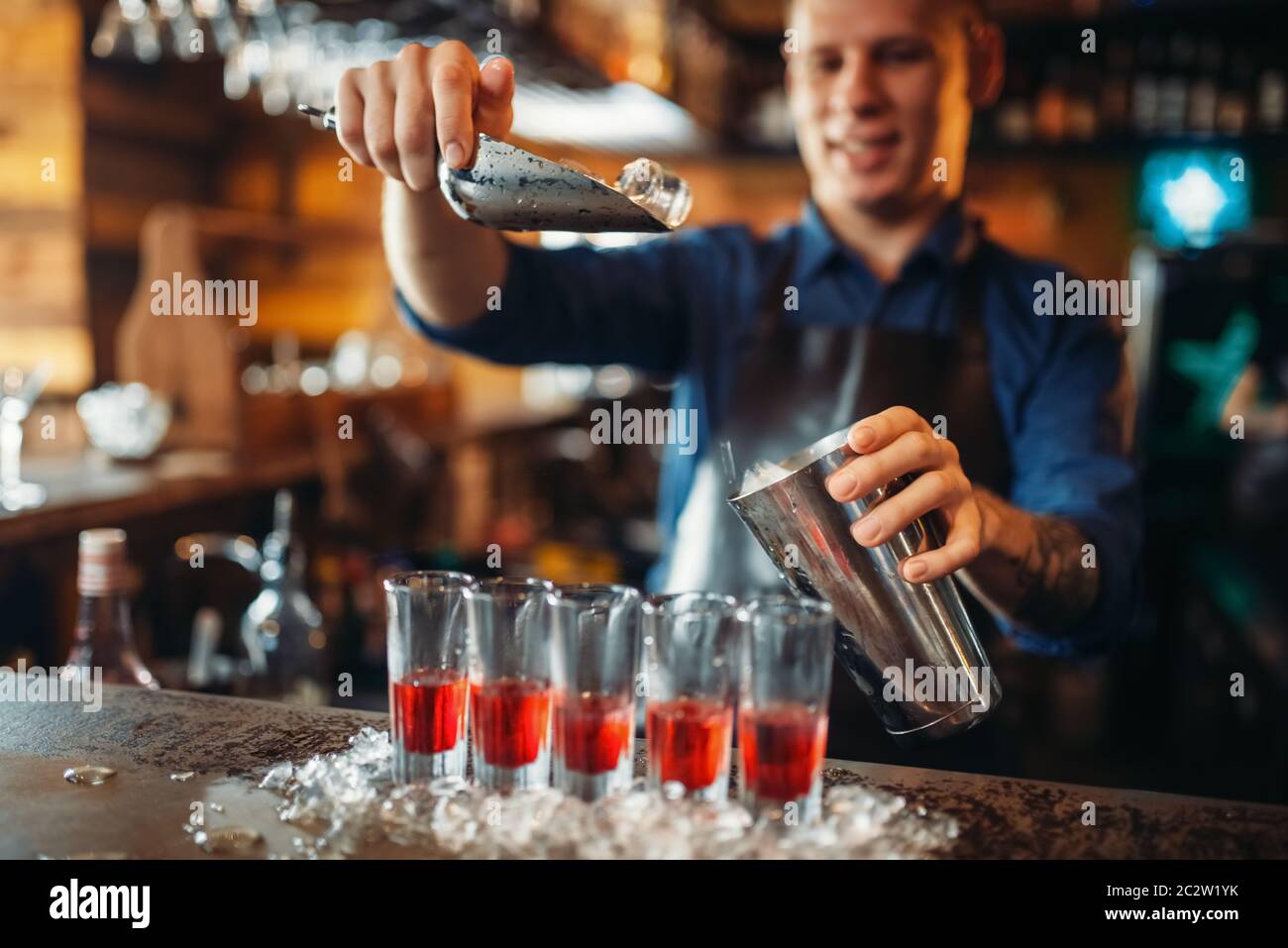 Male barman at the bar counter with glasses standing in ice. Bartender in pub. Barkeeper occupation Stock Photo