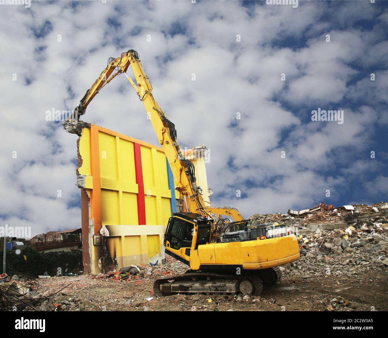 High reach demolition excavator working demolition site. Construction machinery demolishing building. Stock Photo