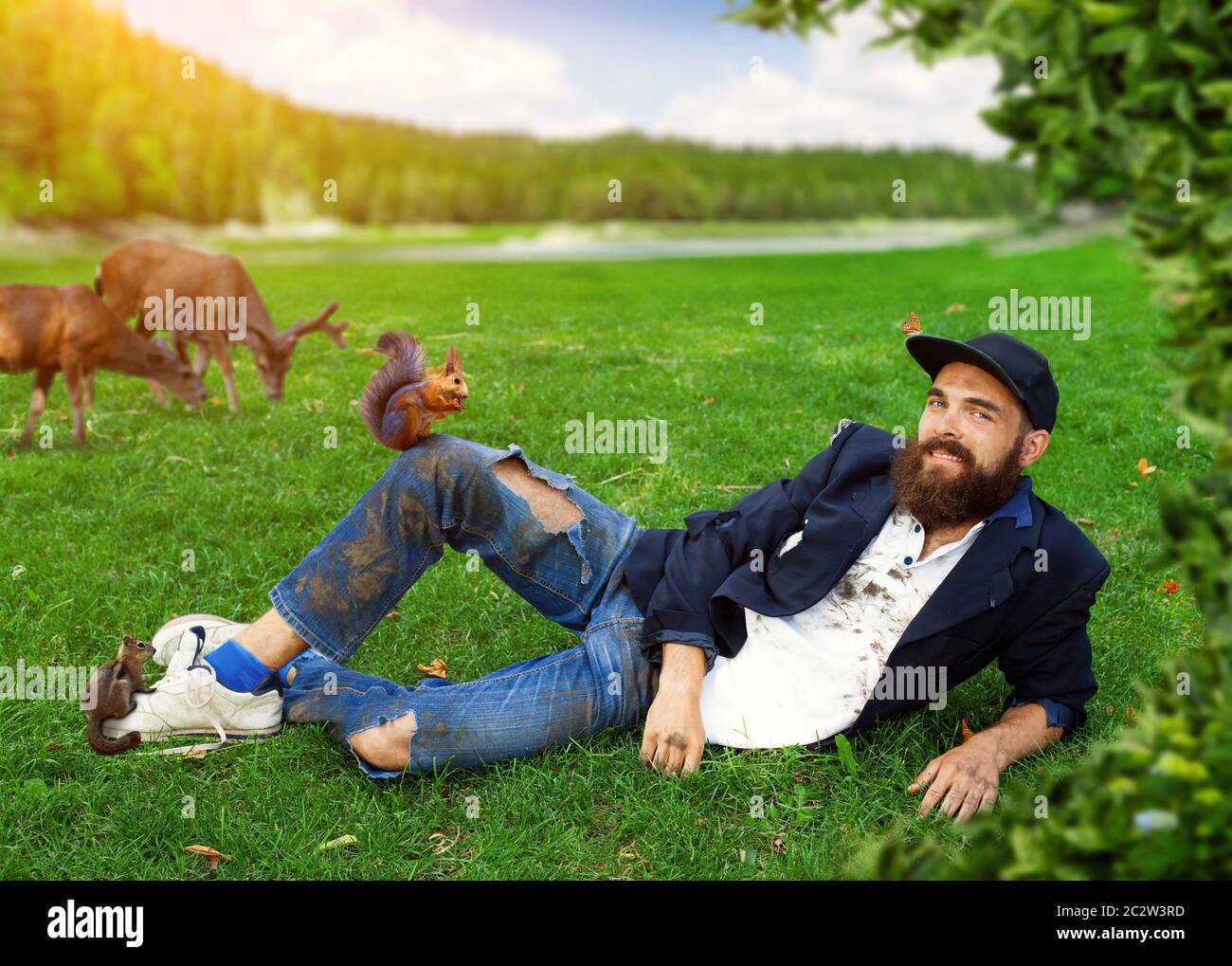 Happy vagrant lying on the lawn with animals Stock Photo