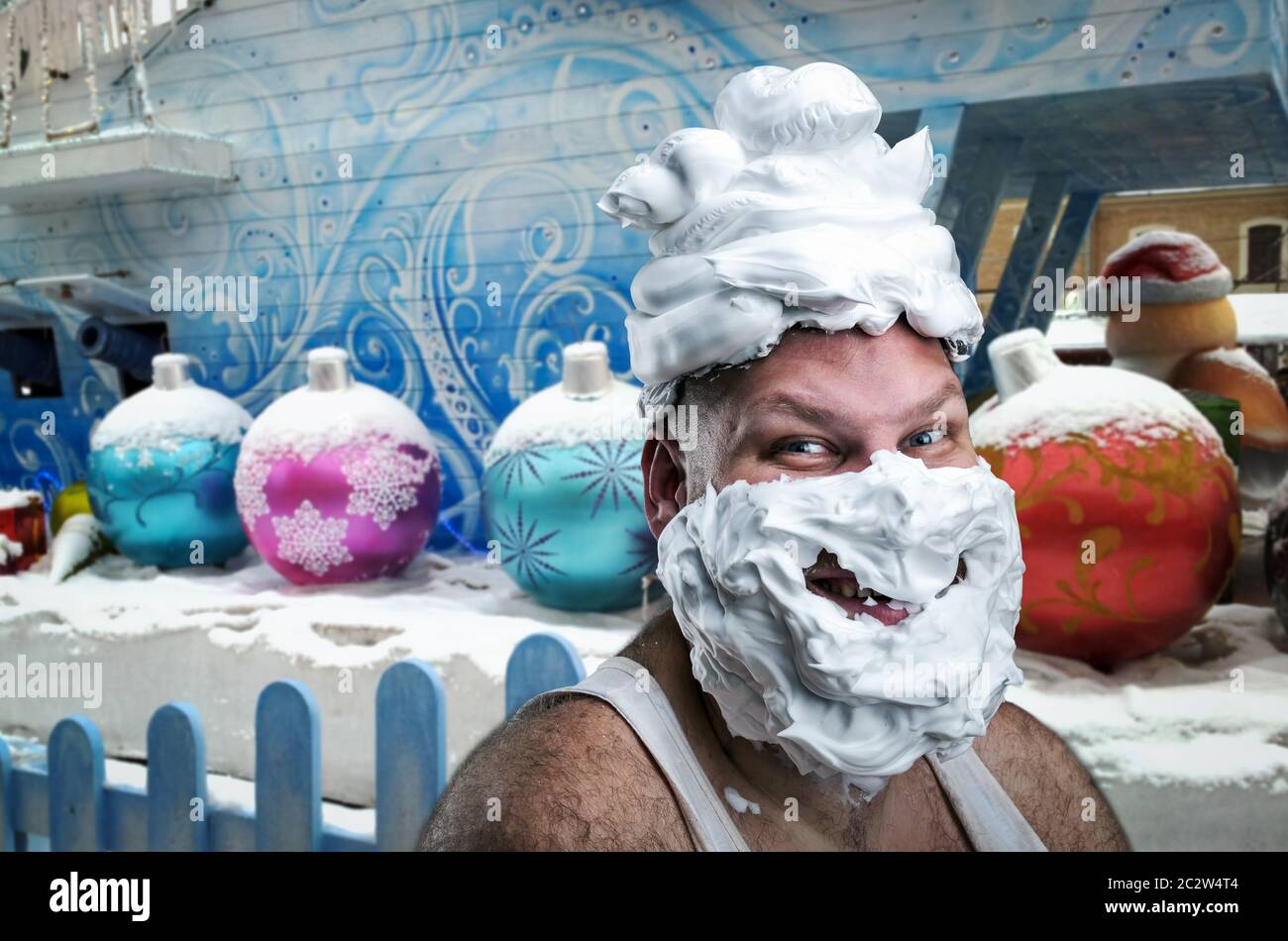Strange smiling man with shaving foam on his face and on his head over winter background Stock Photo