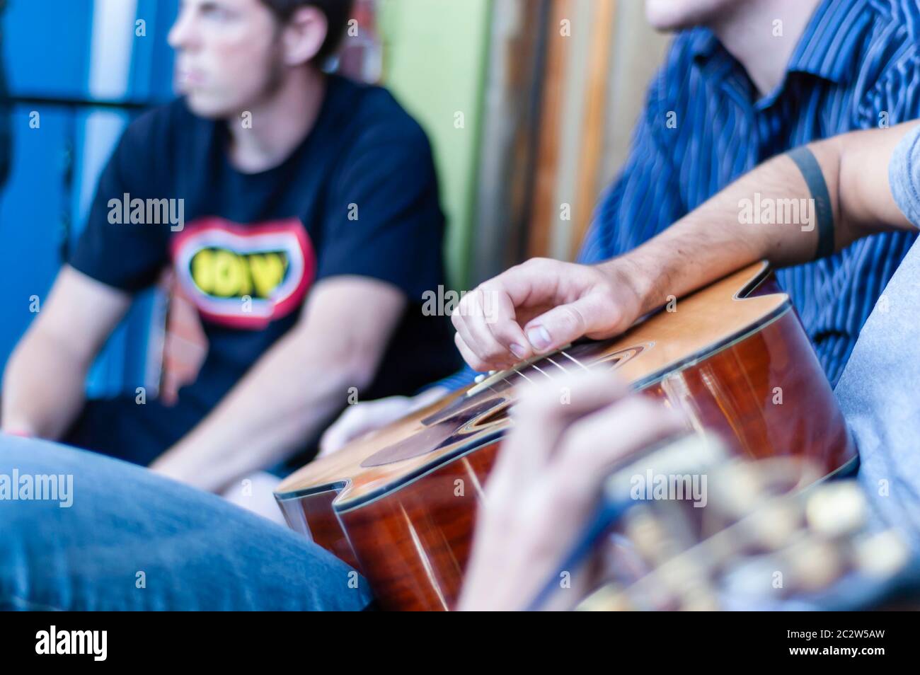A close up of a musicians hand strumming/plucking/thrumming the chords on a guitar. Stock Photo