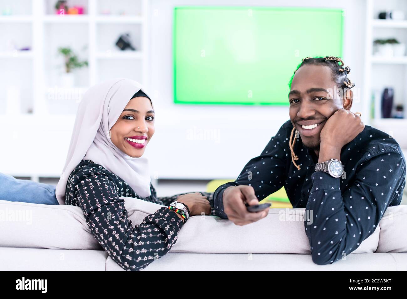 African Couple Sitting On Sofa Watching TV Together Stock Photo - Alamy