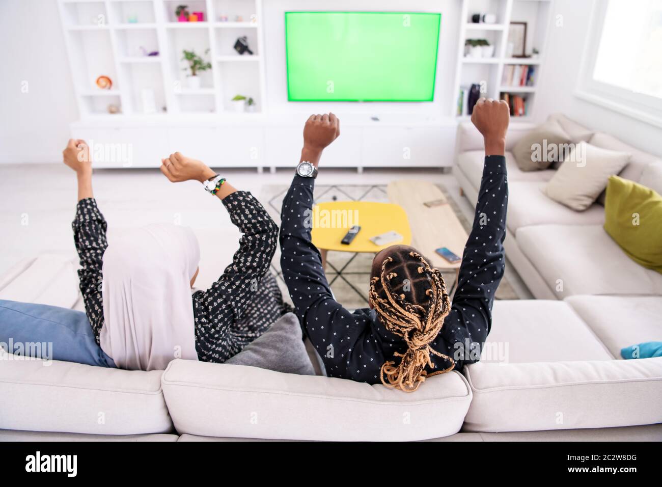 African Couple Sitting On Sofa Watching TV Together Stock Photo - Alamy
