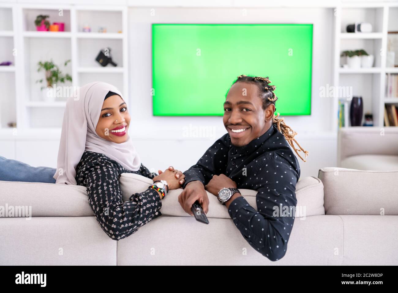 African Couple Sitting On Sofa Watching TV Together Stock Photo - Alamy