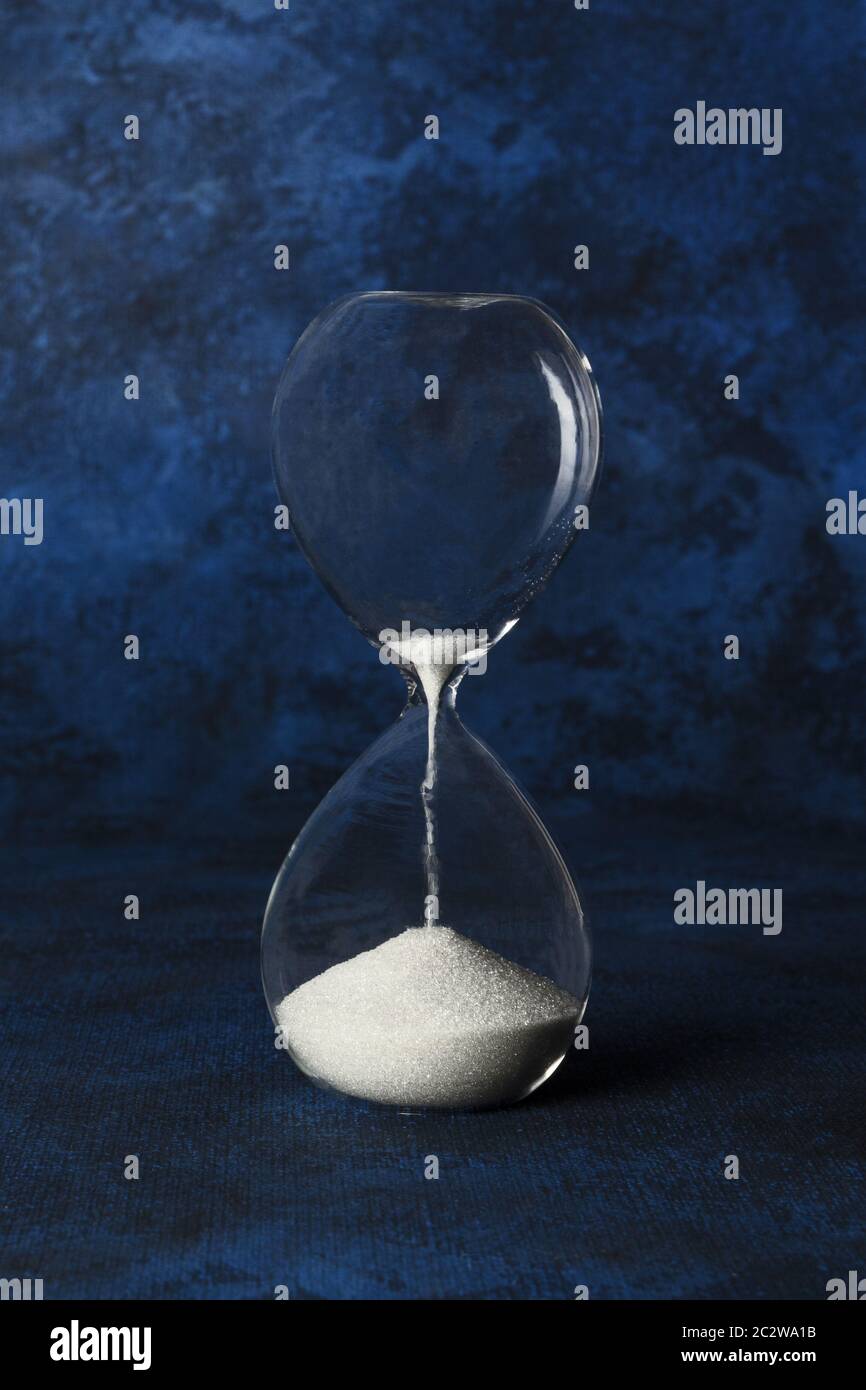 An hourglass on a dark blue background with a place for text. Time management or pressure concept with copy space Stock Photo