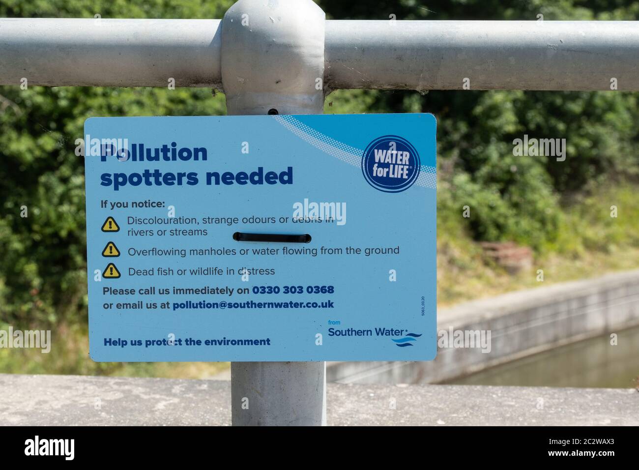 Sign on a canal bridge with the message Pollution Spotters Needed, by Southern Water, UK Stock Photo
