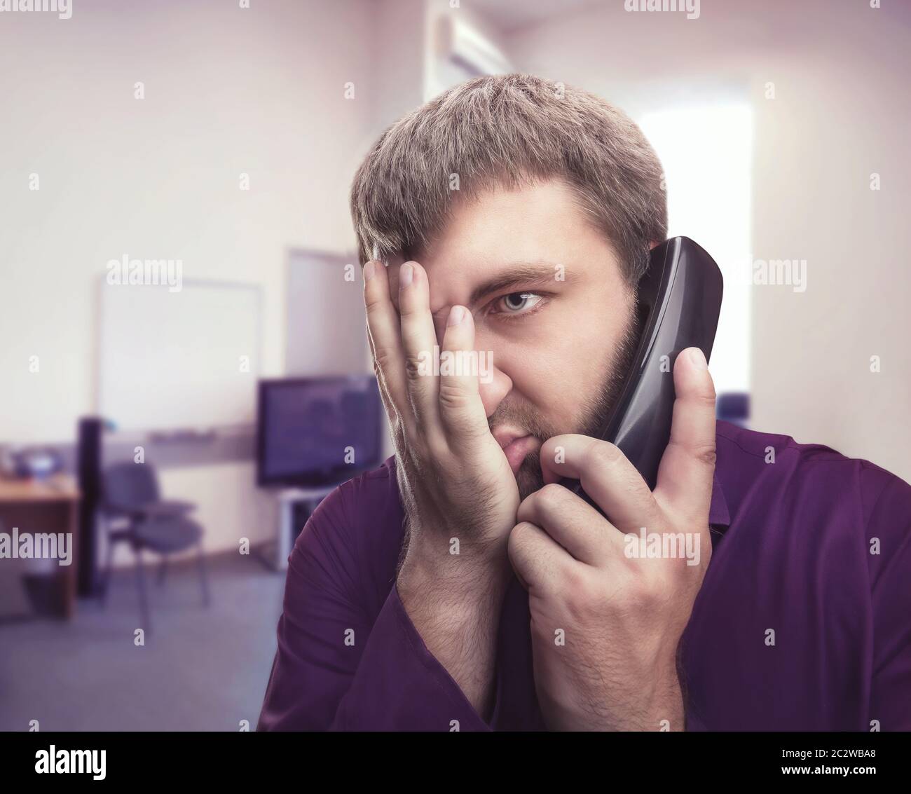 Frustrated man speaks on the phone in the office Stock Photo