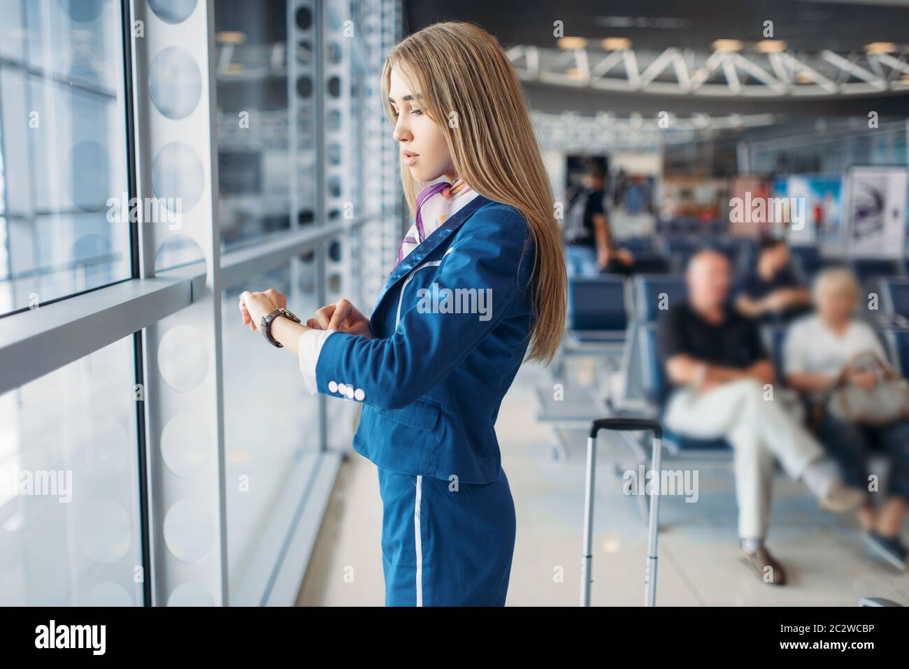 Stewardess legs and suitcase in airport hall. Air hostess with baggage, flight attendant with hand luggage, aviatransportations job Stock Photo