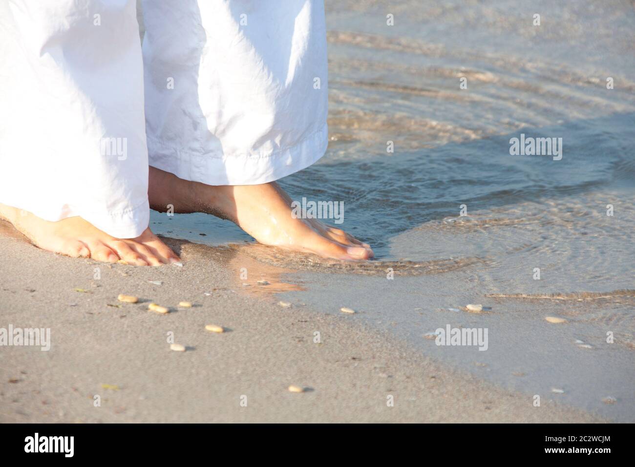 Woman in white walking barefoot on the beach Stock Photo - Alamy