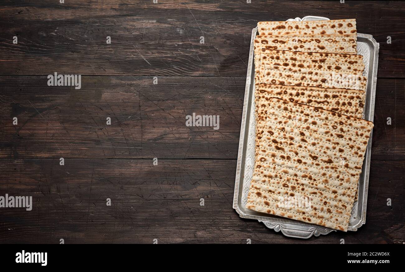 stack of baked square matzoh on brown wooden background, top view, copy space Stock Photo