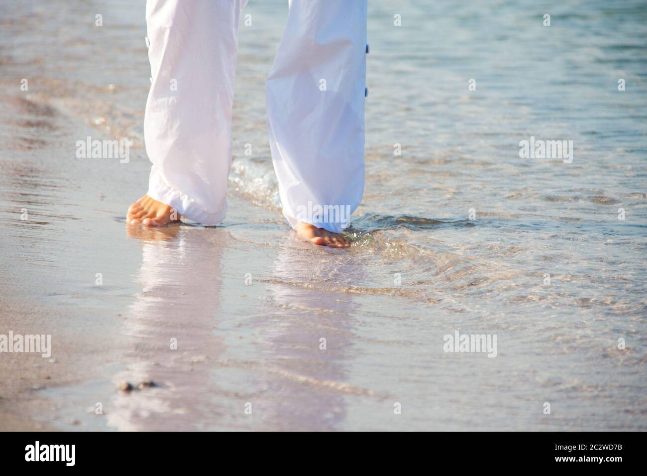 Woman in white walking barefoot on the beach Stock Photo - Alamy