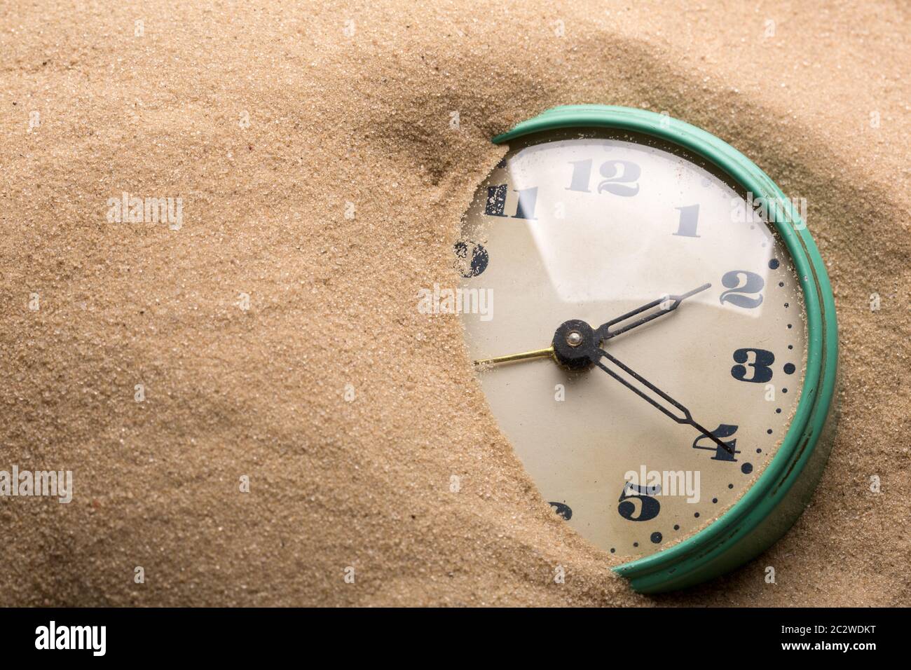 Old alarm clock in sand Stock Photo