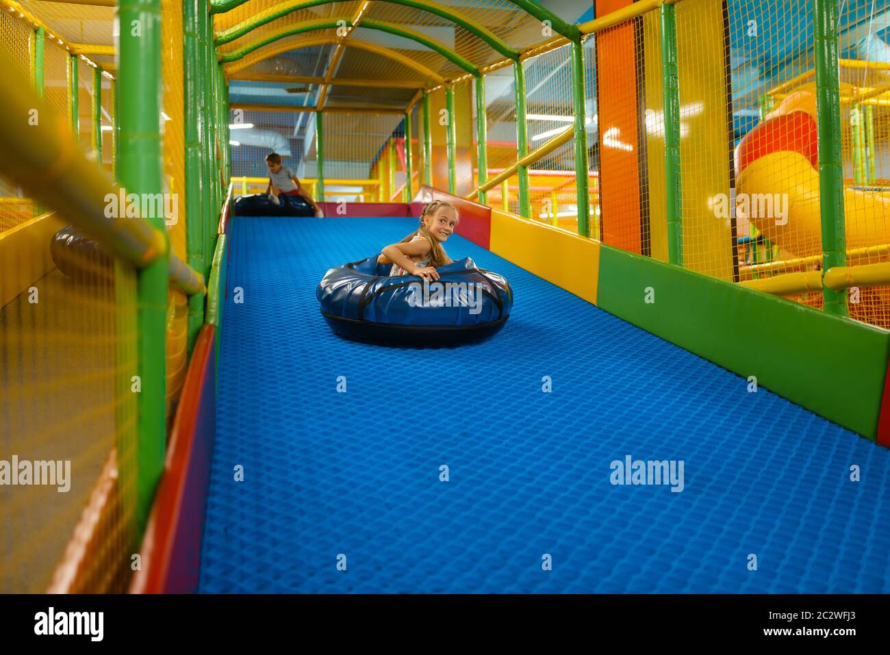 Little girl rides on tubing, playground in entertainment center. Play