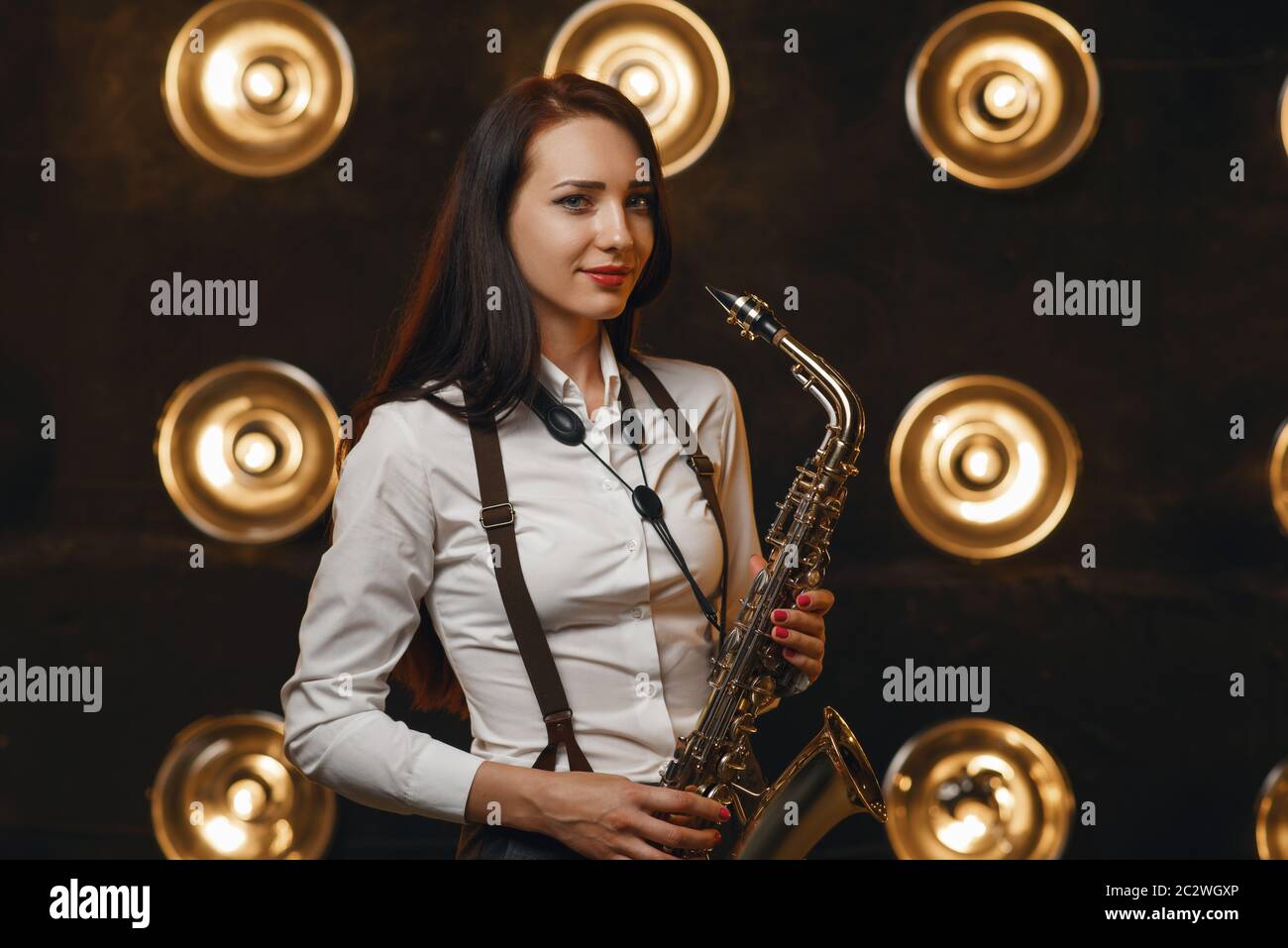 Female saxophonist plays the saxophone on the stage with spotlights