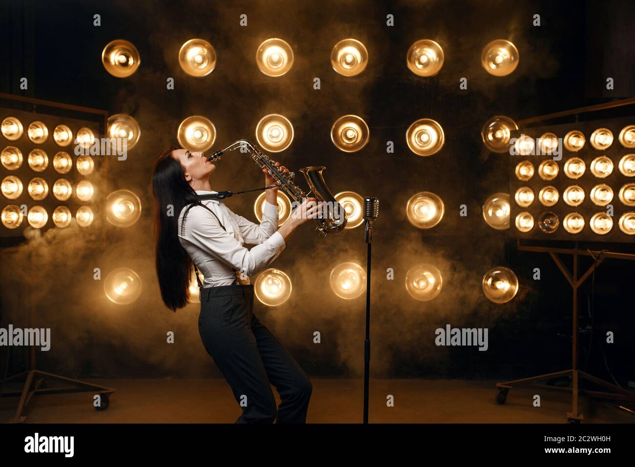 Female saxophonist plays the saxophone on the stage with spotlights