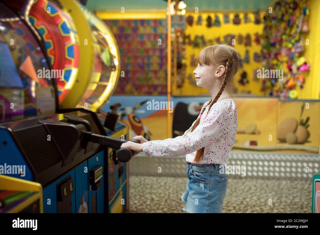 Little girl plays game machine, children entertainment center. Excited