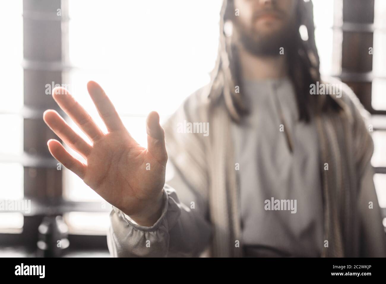 Jesus Christ in white robe reaching out his hand, window with sunlight on  background, peace symbol. Son of God, christian faith Stock Photo - Alamy