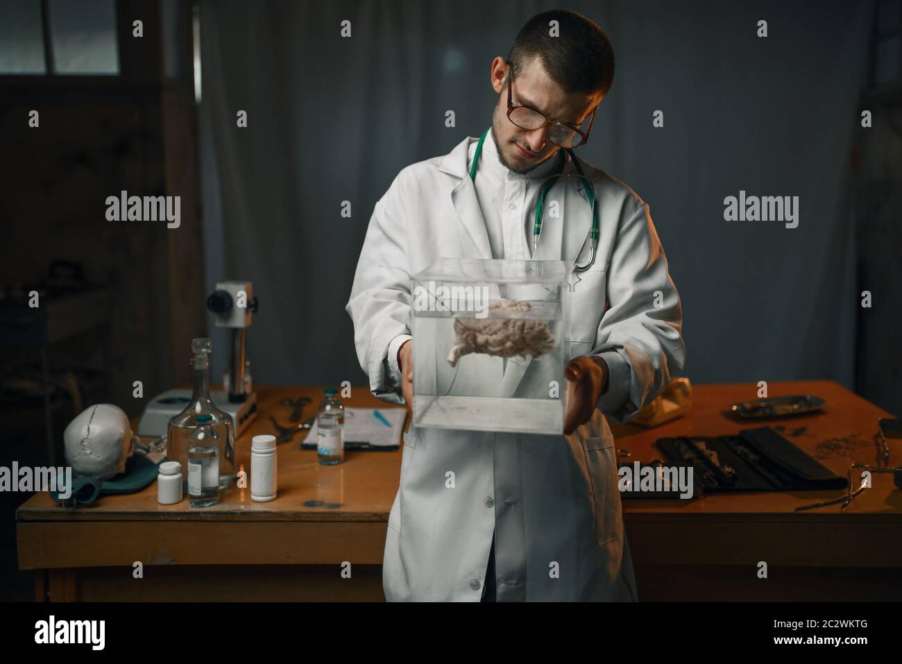 Male psychiatrist in lab coat holds container with the human brain, mental hospital. Doctor in clinic for the mentally ill Stock Photo