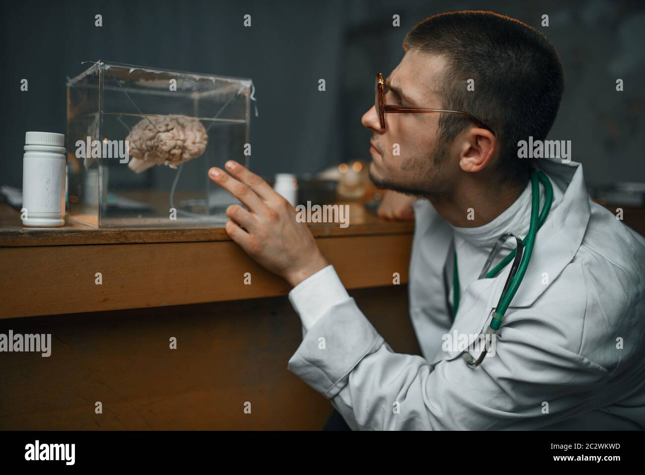 Male psychiatrist in lab coat holds container with the human brain, mental hospital. Doctor in clinic for the mentally ill Stock Photo