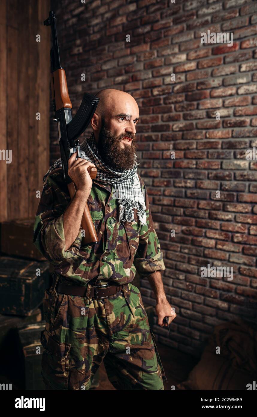 Terrorist in uniform holds kalashnikov rifle in hands, male mojahed with  weapon. Terrorism and terror, soldier in khaki camouflage, barrels of fuel  or Stock Photo - Alamy