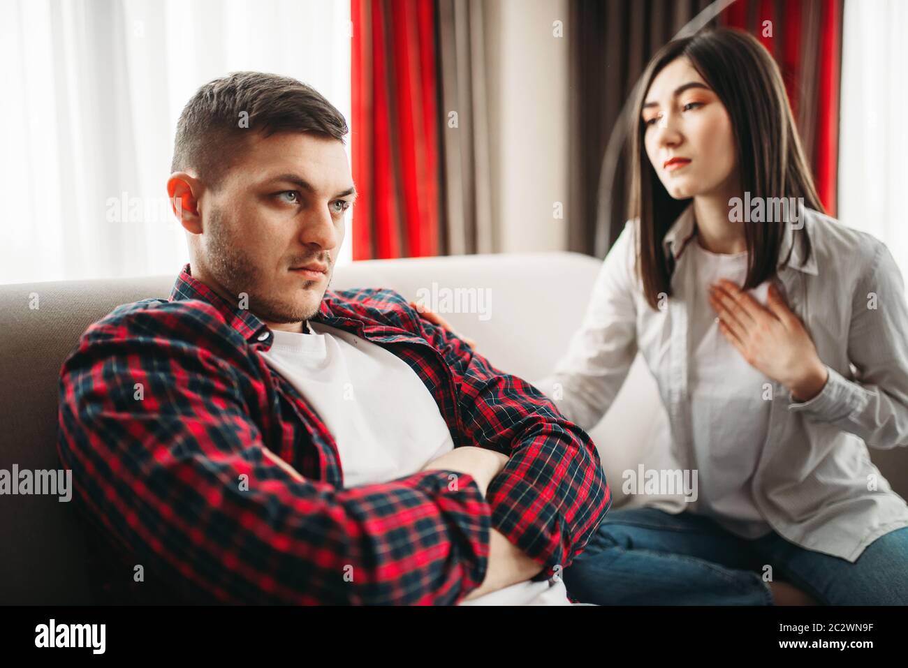 Wife asks her husband for forgiveness after family quarrel. Man and woman in abuse, couple in conflict Stock Photo
