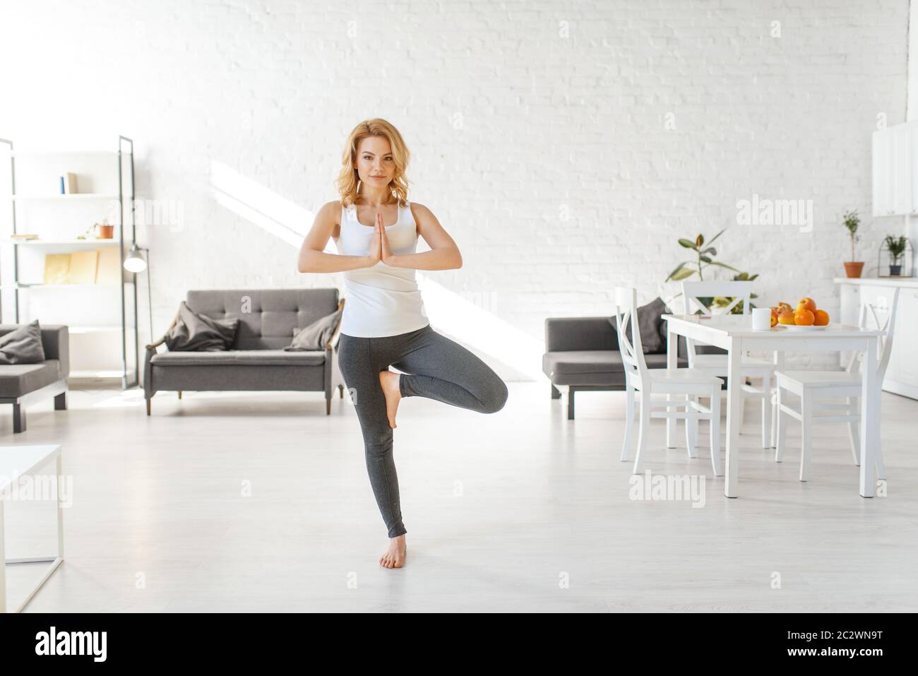 Yuong woman sitting on the floor in yoga pose, living room interior in ...