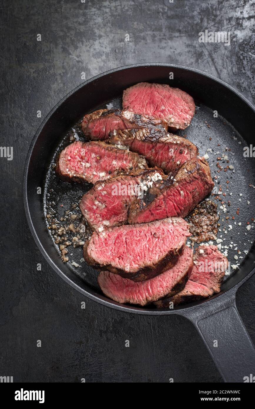 Barbecue dry aged wagyu sirloin beef steak sliced with salt and pepper as top view on a gray