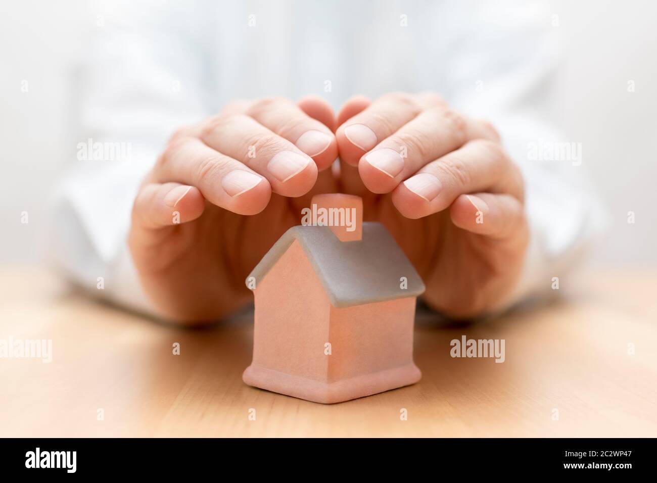 Property insurance. House miniature covered by hands Stock Photo