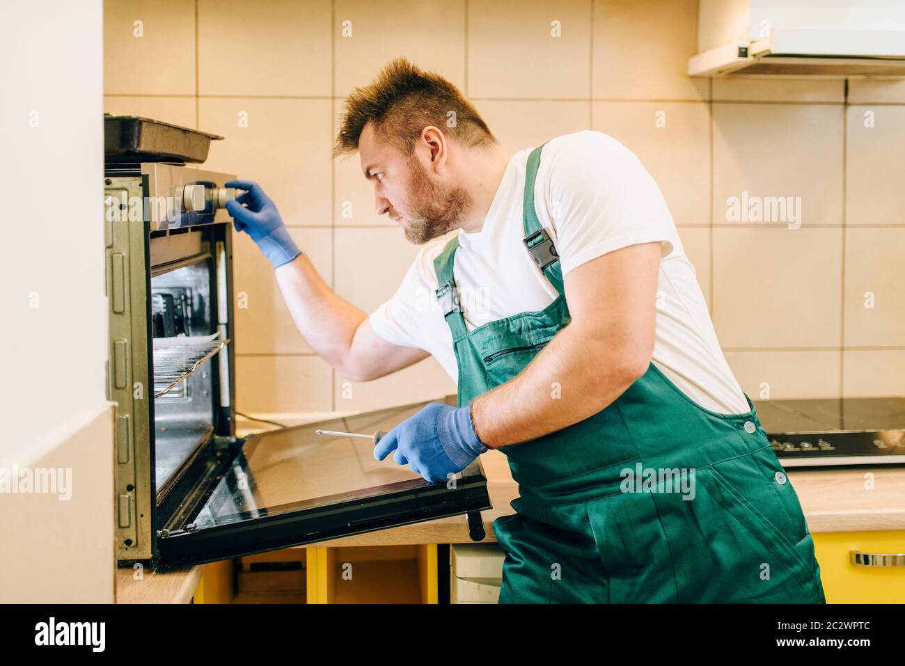 Repairs Technesian Repairman in uniform checks the oven, technician. Professional worker ...