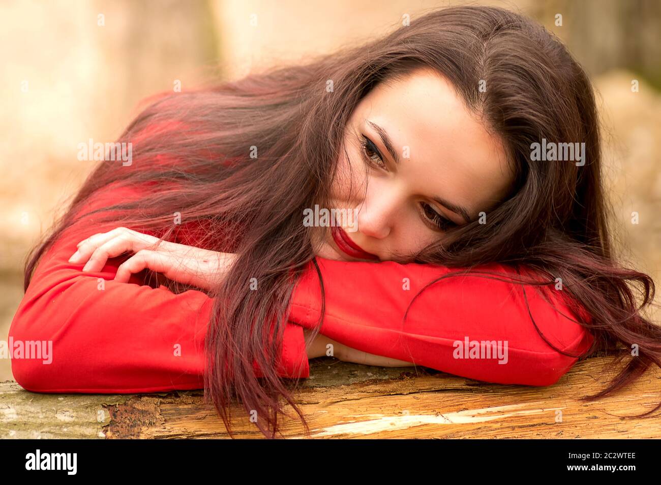 Pretty young woman resting on a wood log Stock Photo - Alamy