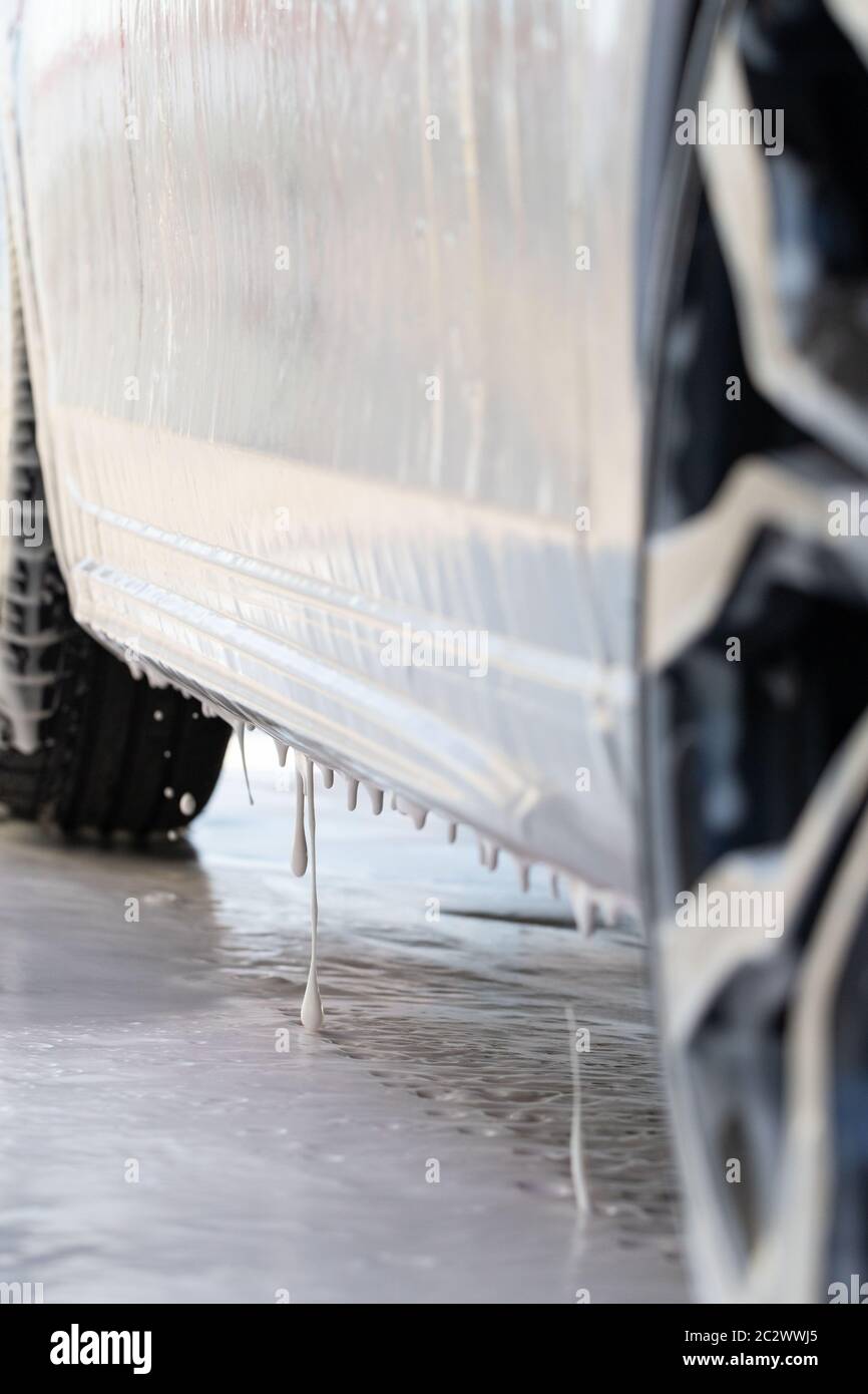 Close up of car is covered with foam at self-service car wash. Bottom view. Stock Photo