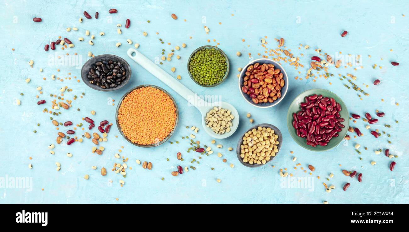 Legumes, overhead panoramic shot on a blue background. Vibrant pulses including colourful beans, lentils, soybeans, chickpeas, a Stock Photo