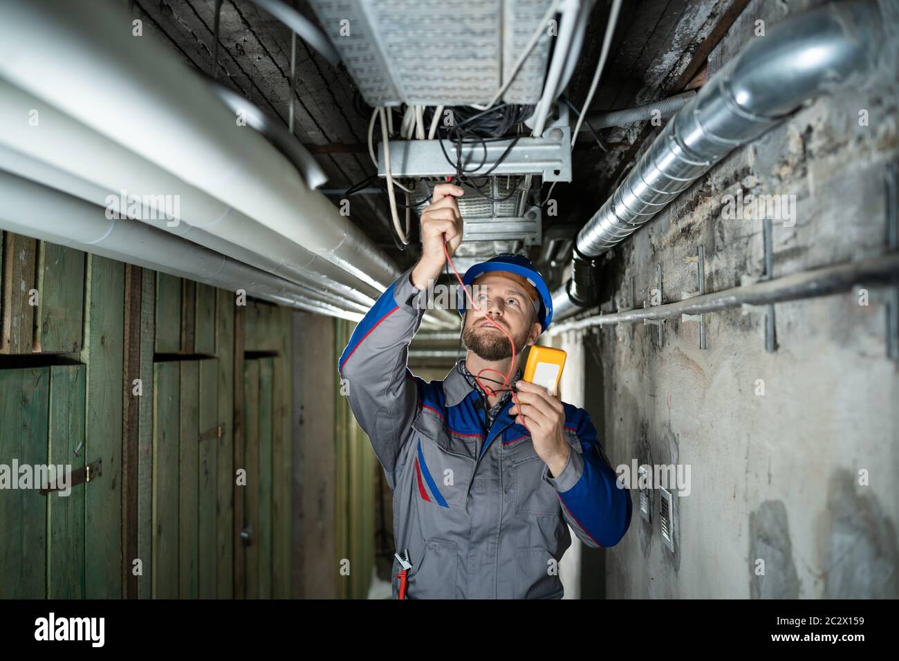 Male Worker Wearing Hard Hat Using Multimeter Stock Photo