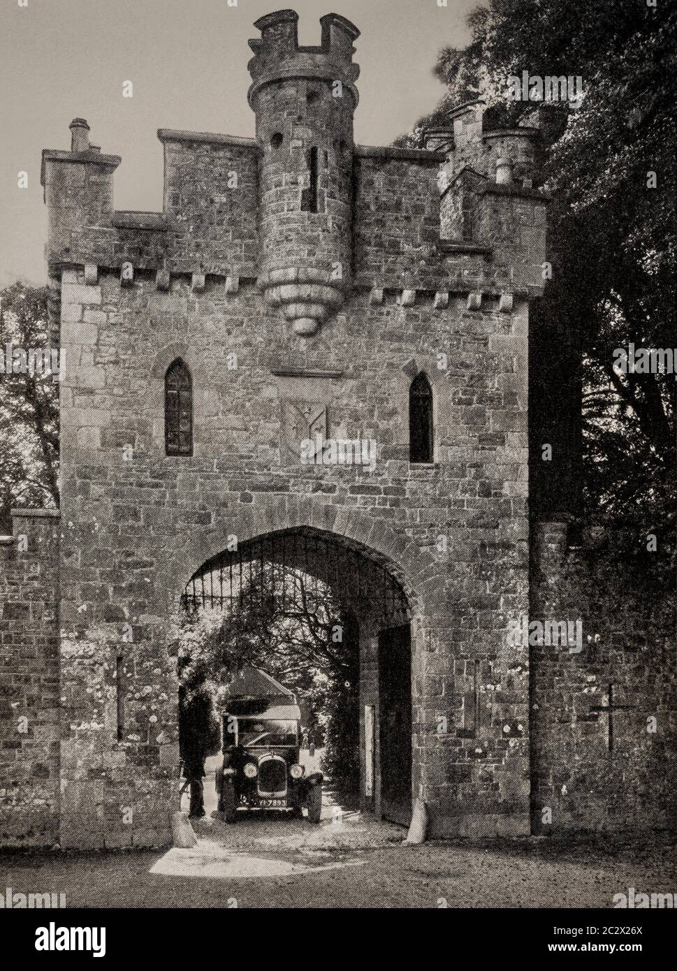 An early 1920's view of classic car leaving the 18th century Mock Tudor Gateway to Slane Castle, in County Meath, Ireland. Originally photographed by Clifton Adams (1890-1934) for 'Ireland: The Rock Whence I Was Hewn', a National Geographic Magazine feature from March 1927. Stock Photo