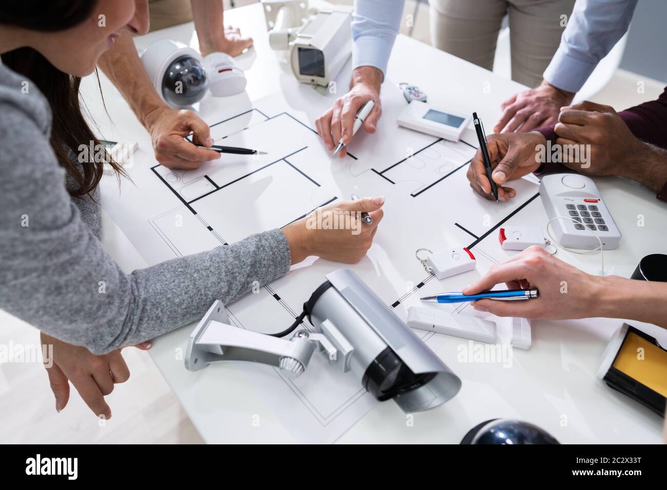 Group Of Security Engineers Working On Blueprint With Security Equipment On Table Stock Photo