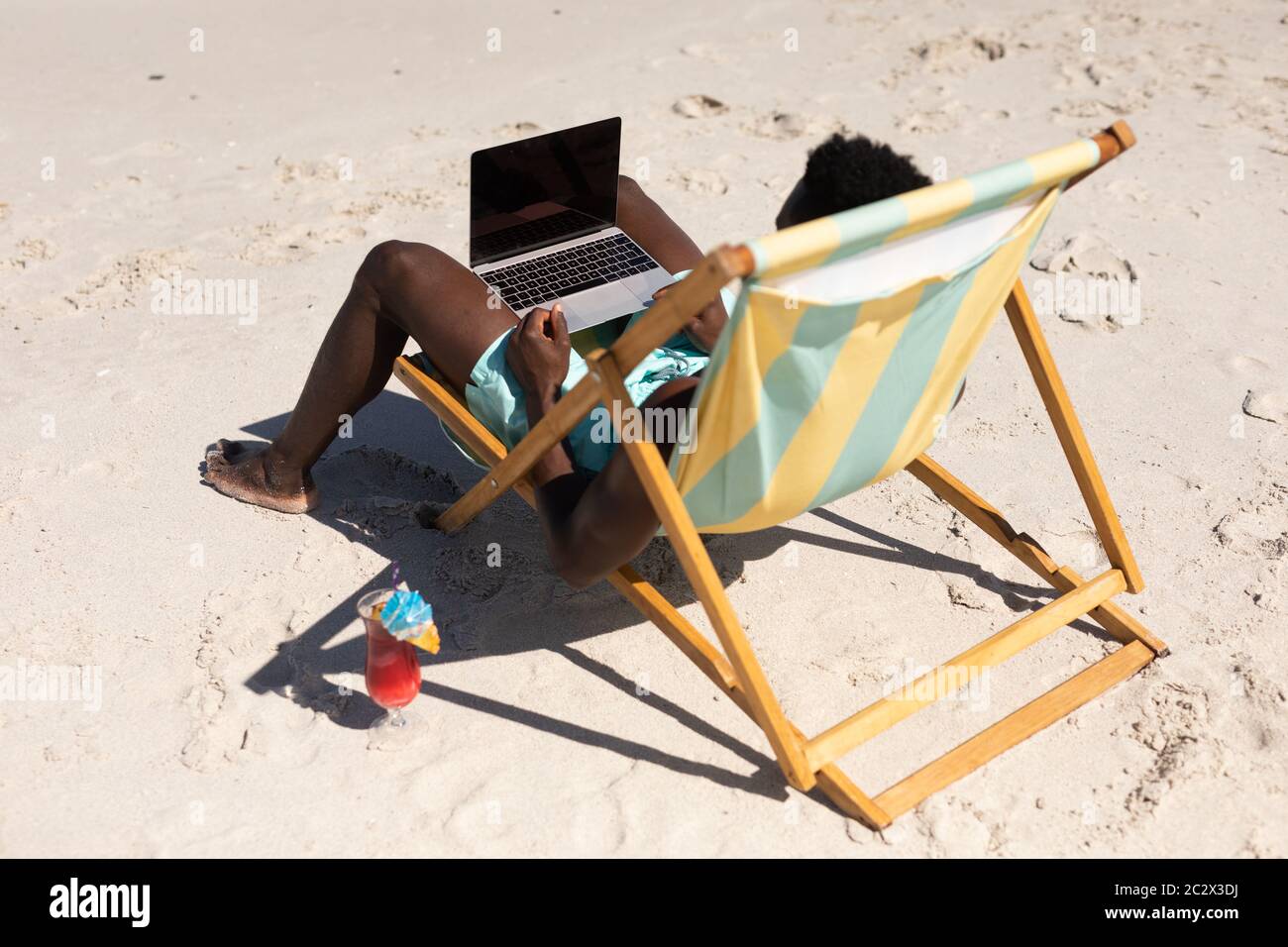 African American man using computer on the beach Stock Photo