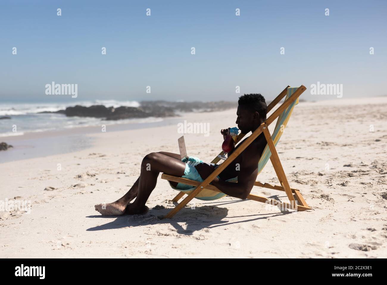 African American man using computer on the beach Stock Photo