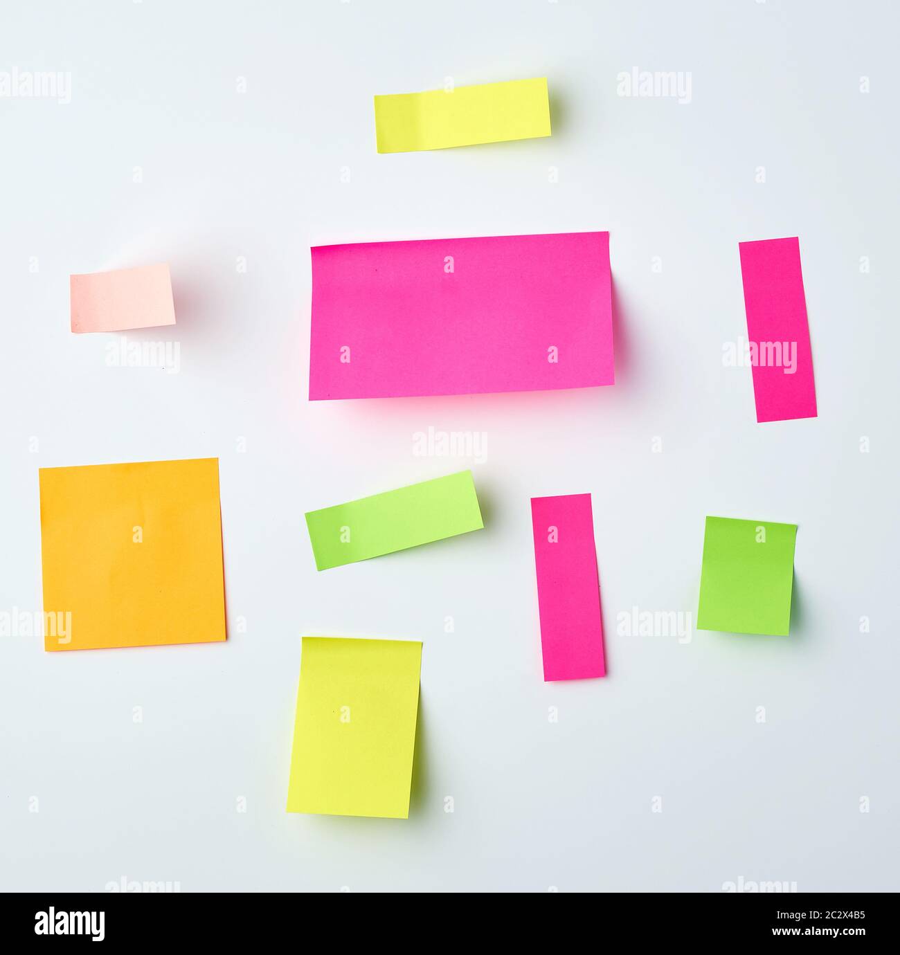 various blank paper multicolored stickers on a white wall, close up Stock Photo