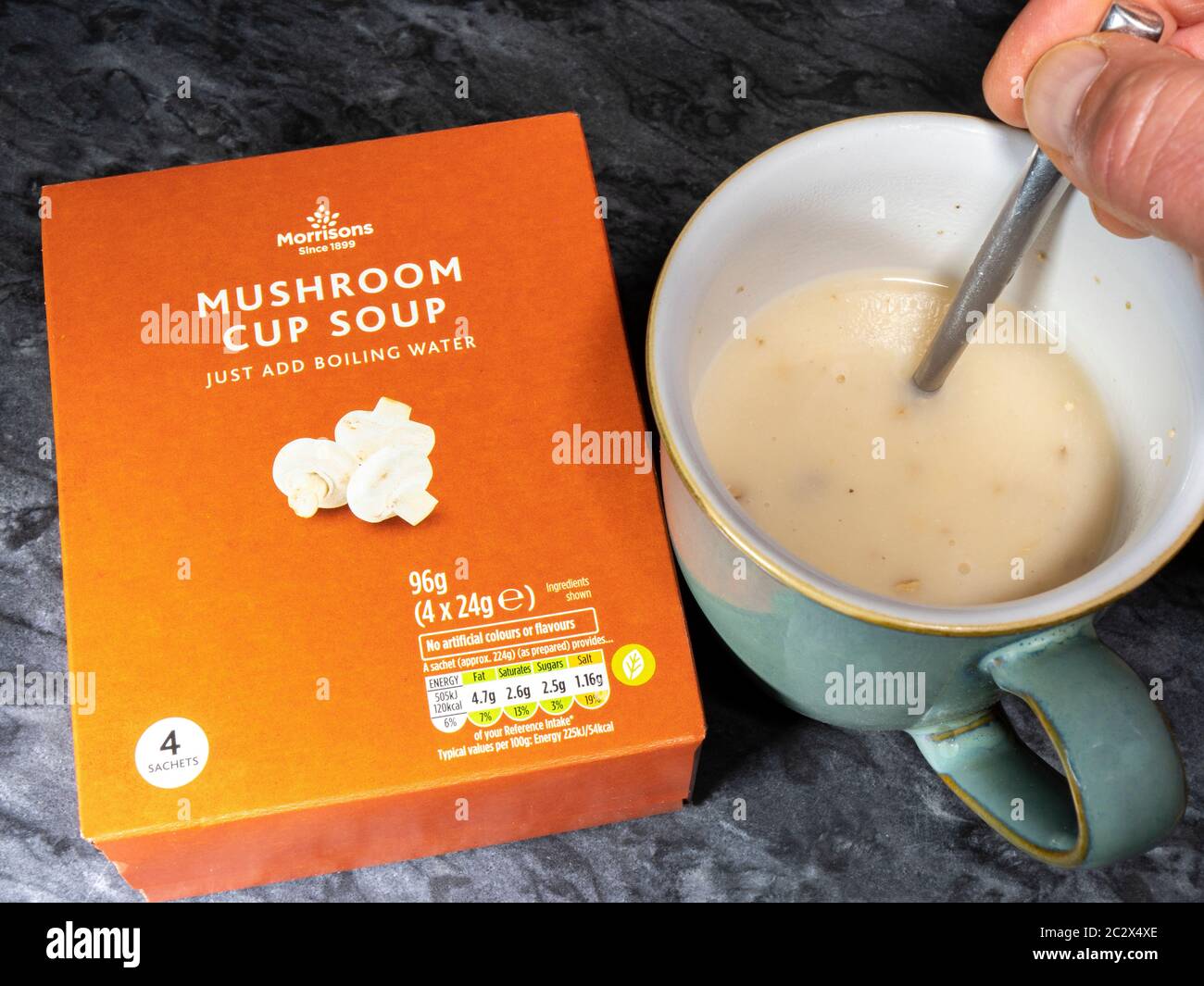 Morrisons own brand mushroom soup – a product box and a sachet of dry soup mixed with with boiling water, being stirred in a cup. Stock Photo