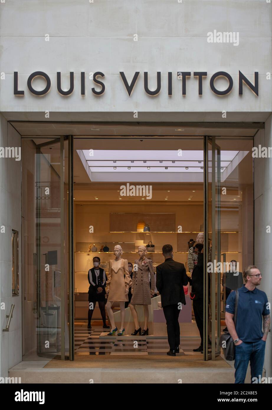 Shoppers in masks wait in line at the Louis Vuitton store in the