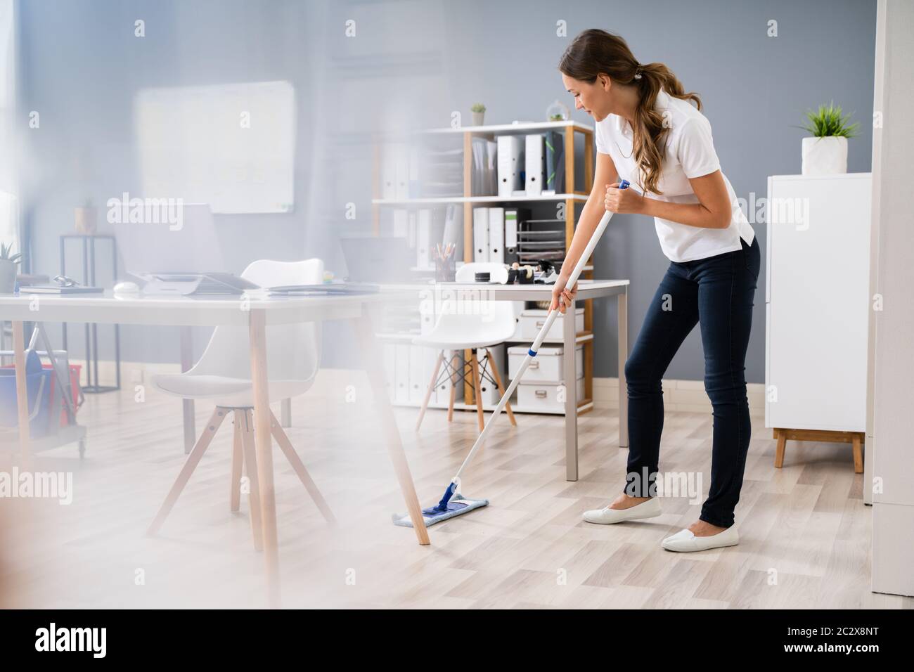 Full Length Of Female Janitor Mopping Floor In Office Stock Photo