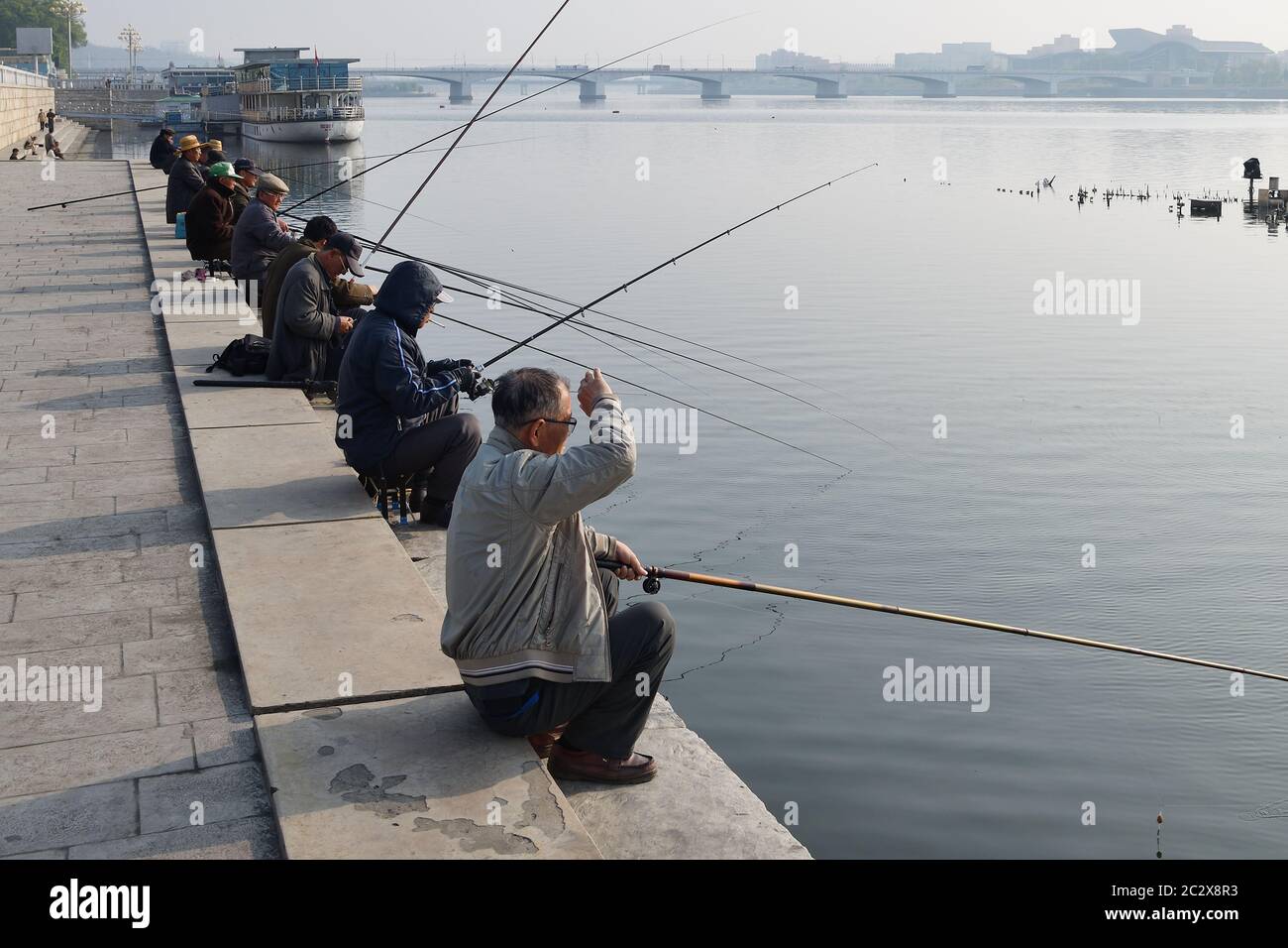 Pyongyang, North Korea - May 1, 2019: Local fishermen catch a fish on waterfront on Kim Il Sung square at the sunrise Stock Photo