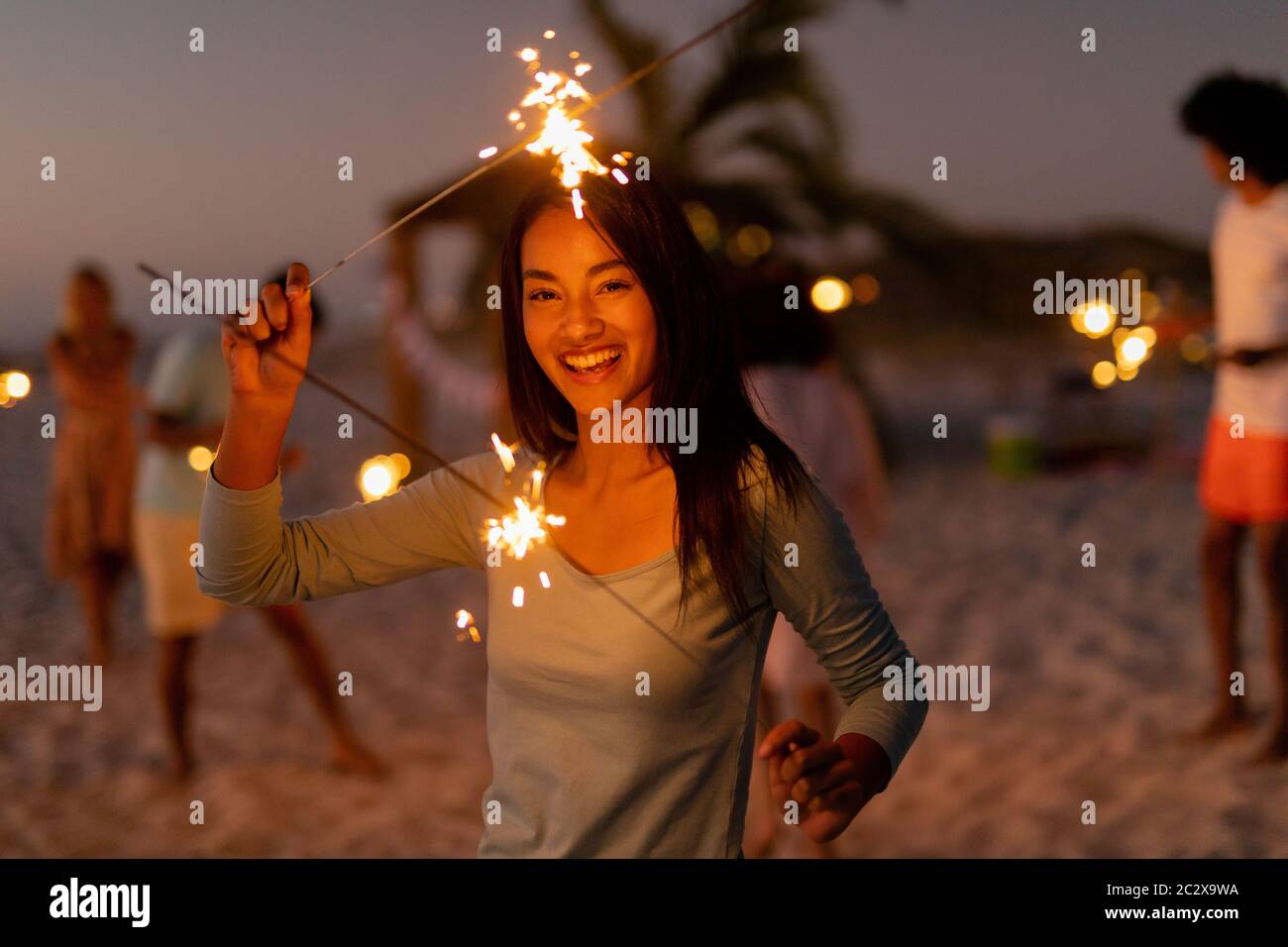 Multi-ethnic group of male and female dancing with firework stick Stock Photo