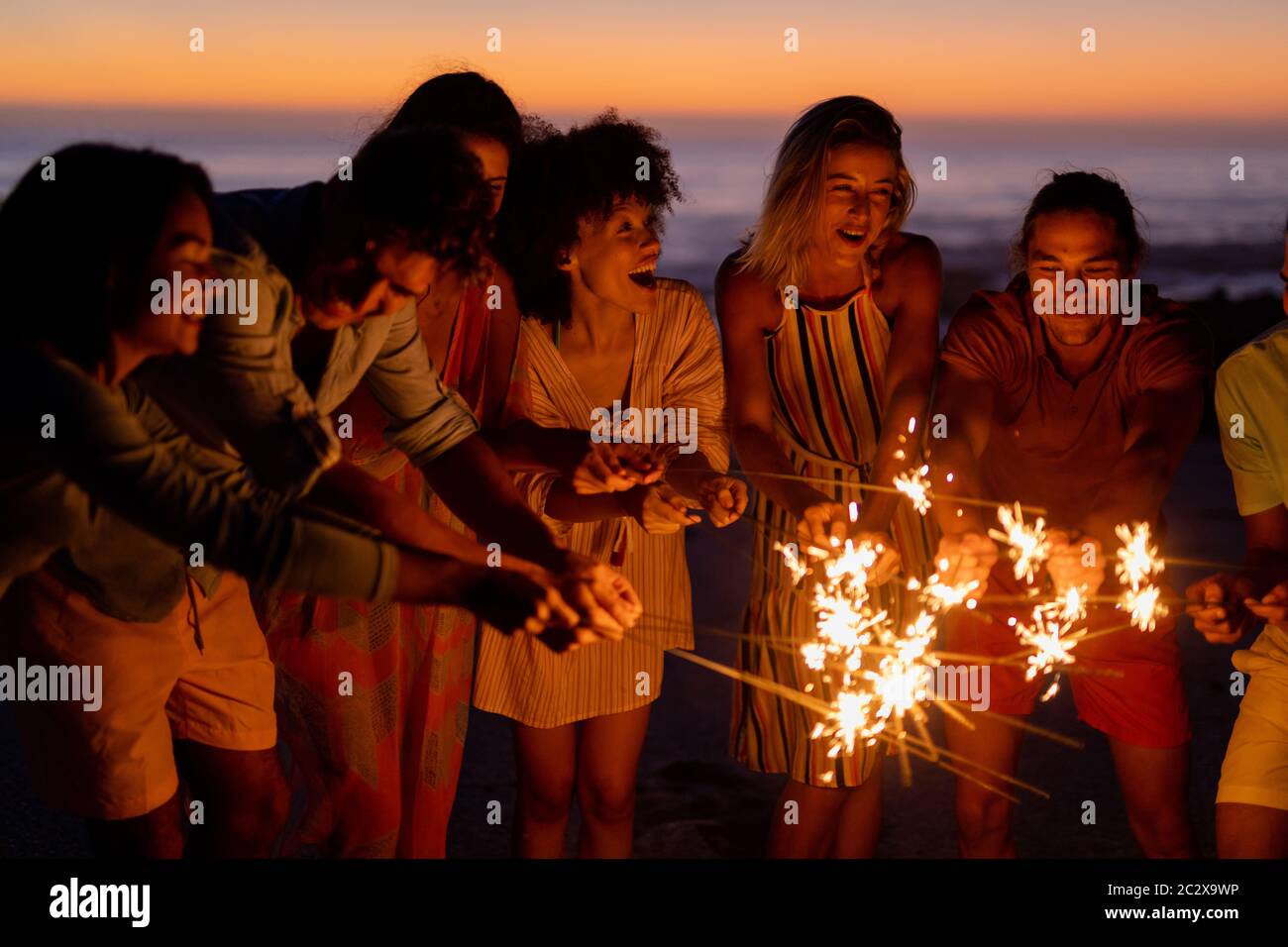 Multi-ethnic group of male and female dancing with firework stick Stock Photo