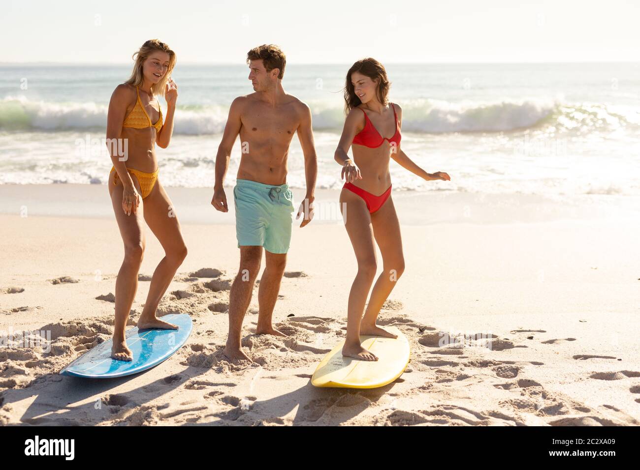 Caucasian group of friends surfing on the beach Stock Photo