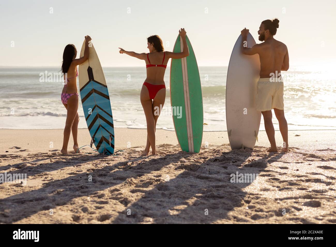 Multi-ethnic group of male and female, surfing on the beach Stock Photo